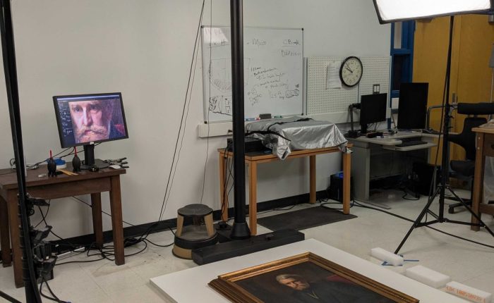 Photography studio with portrait painting on a floor platform surrounded by lights and camera